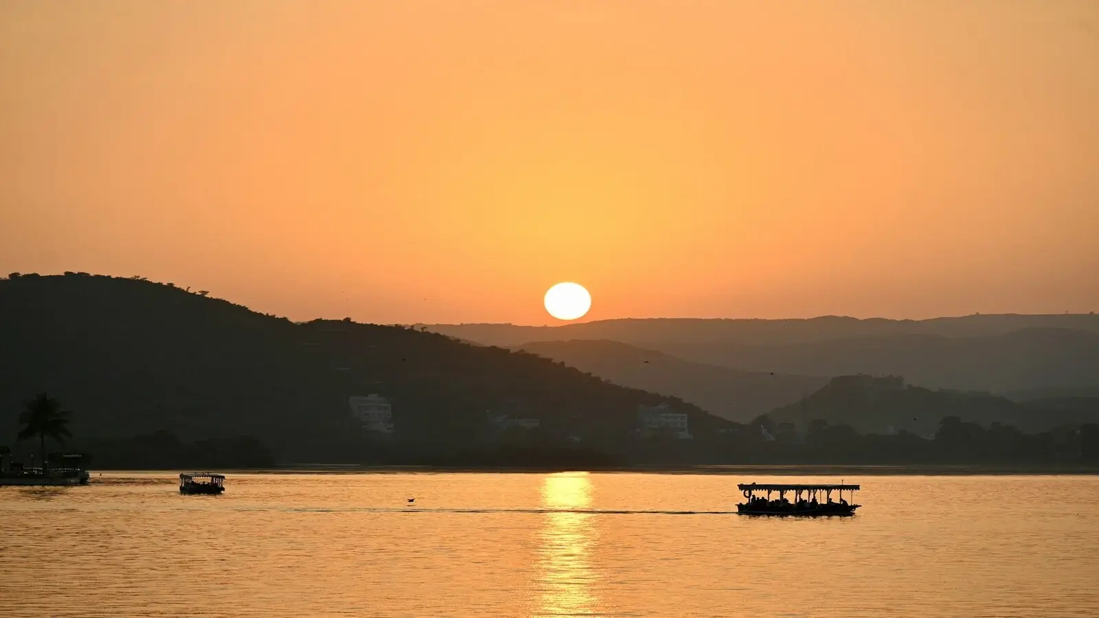Golden sunset over Lake Pichola with City Palace silhouette in Udaipur Rajasthan