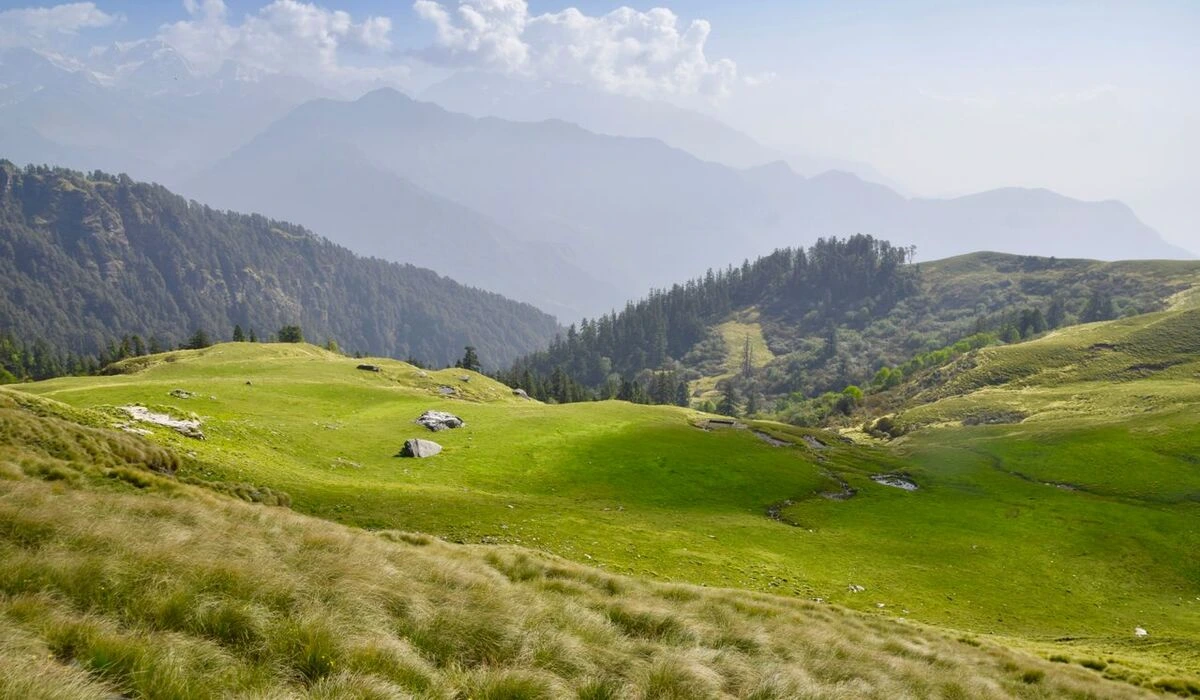 Chopta meadow Uttarakhand in September with green hills and Himalayan peaks in background